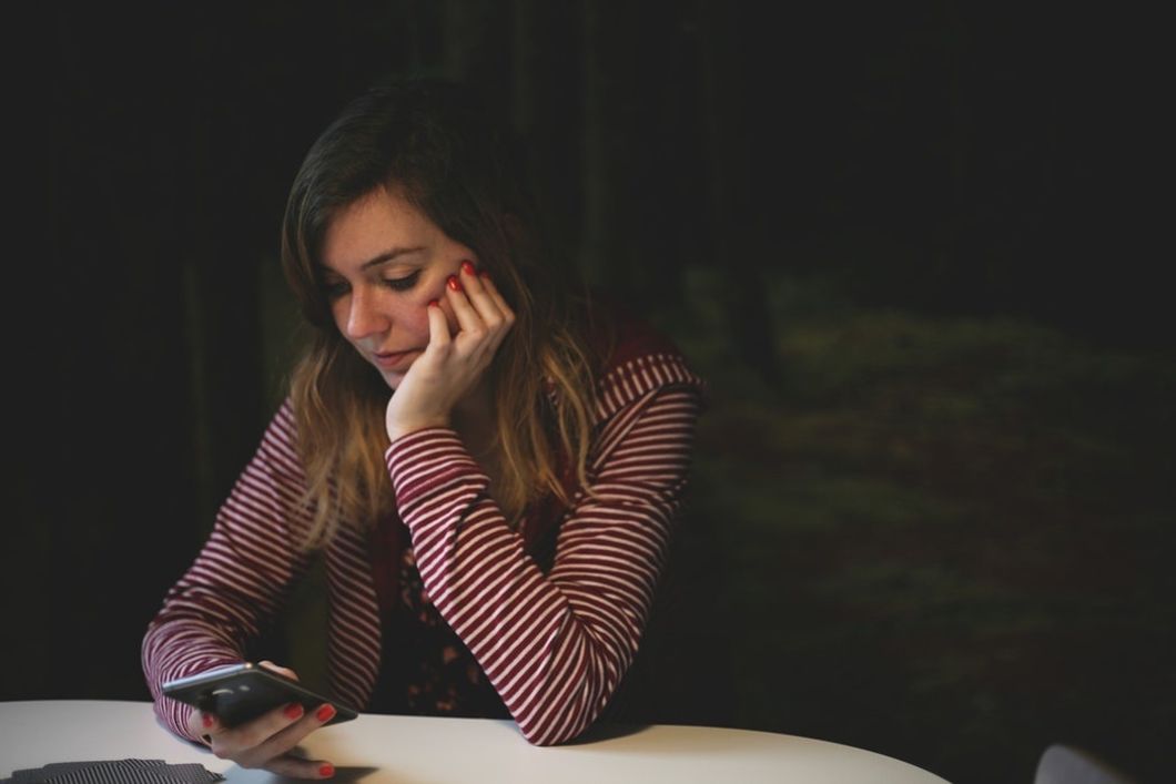 girl sitting at table looking at cell phone