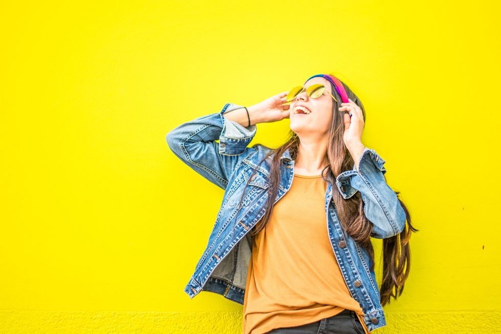 girl smiling and posing in front of a yellow wall