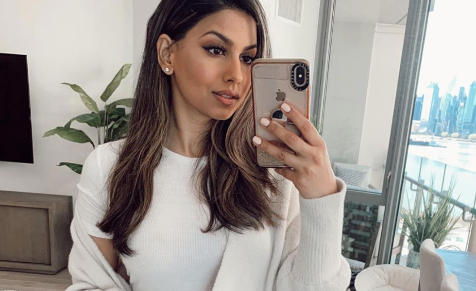 girl smiling and taking selfie in mirror wearing white t-shirt and cardigan