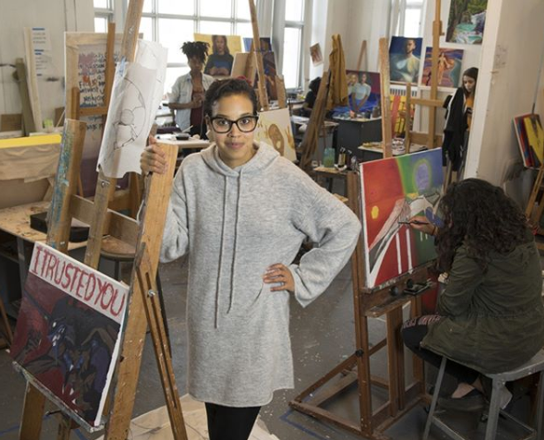 Girl standing next to a painting in an art class