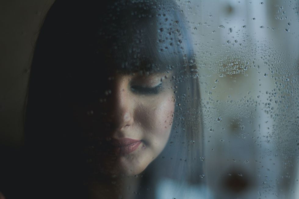 Girl staring out window at rain