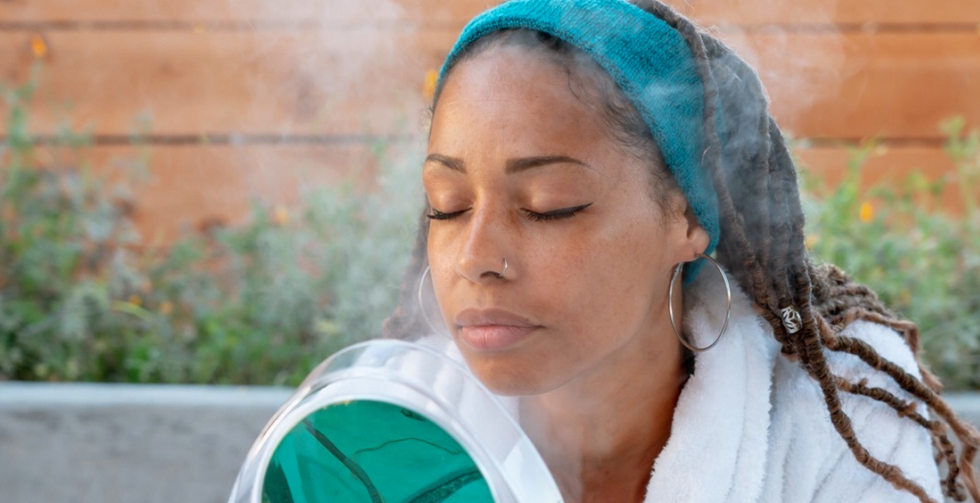 girl wearing blue headband and hoop earrings steaming her face