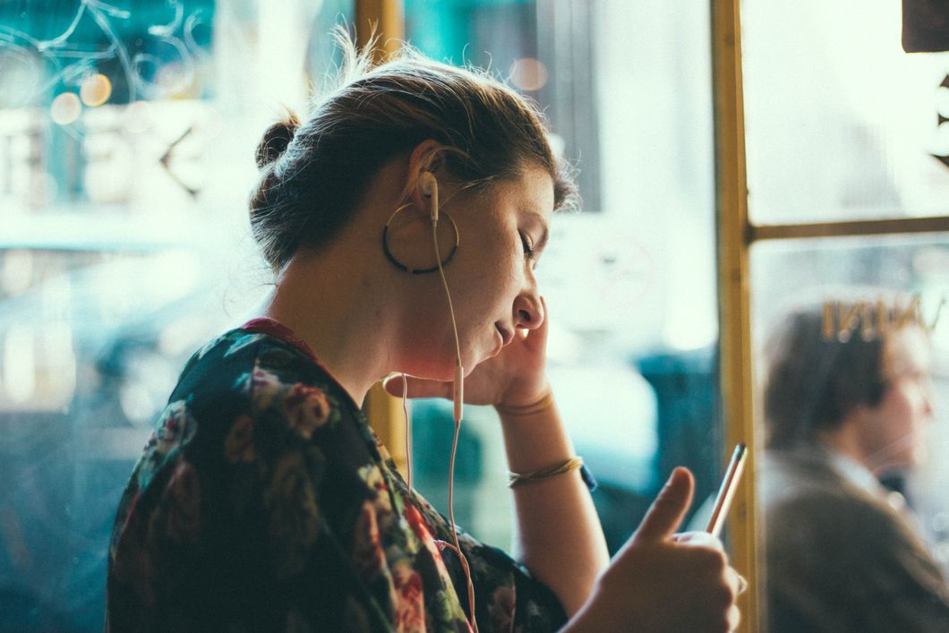 Girl wearing earbuds and scrolling on phone