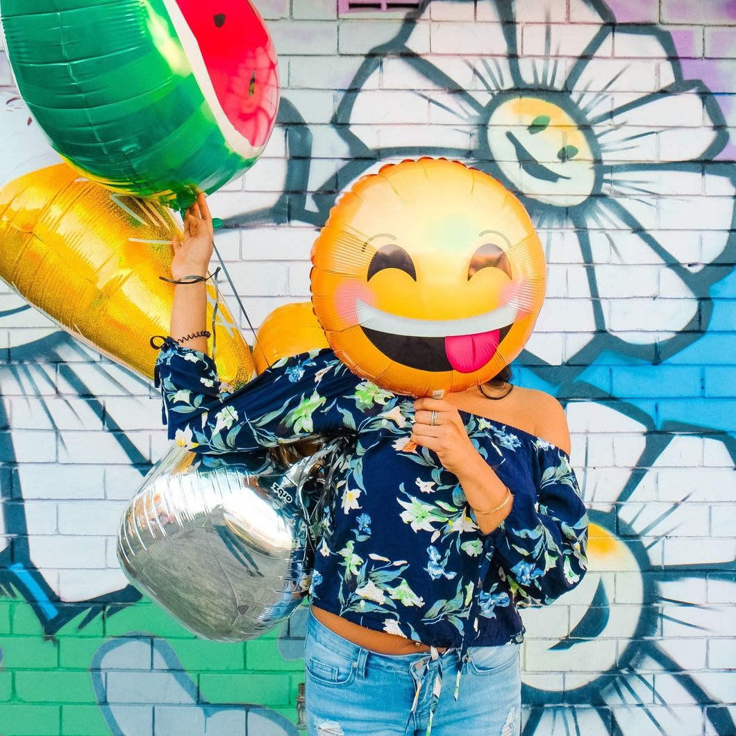 Girl with emoji balloon over face