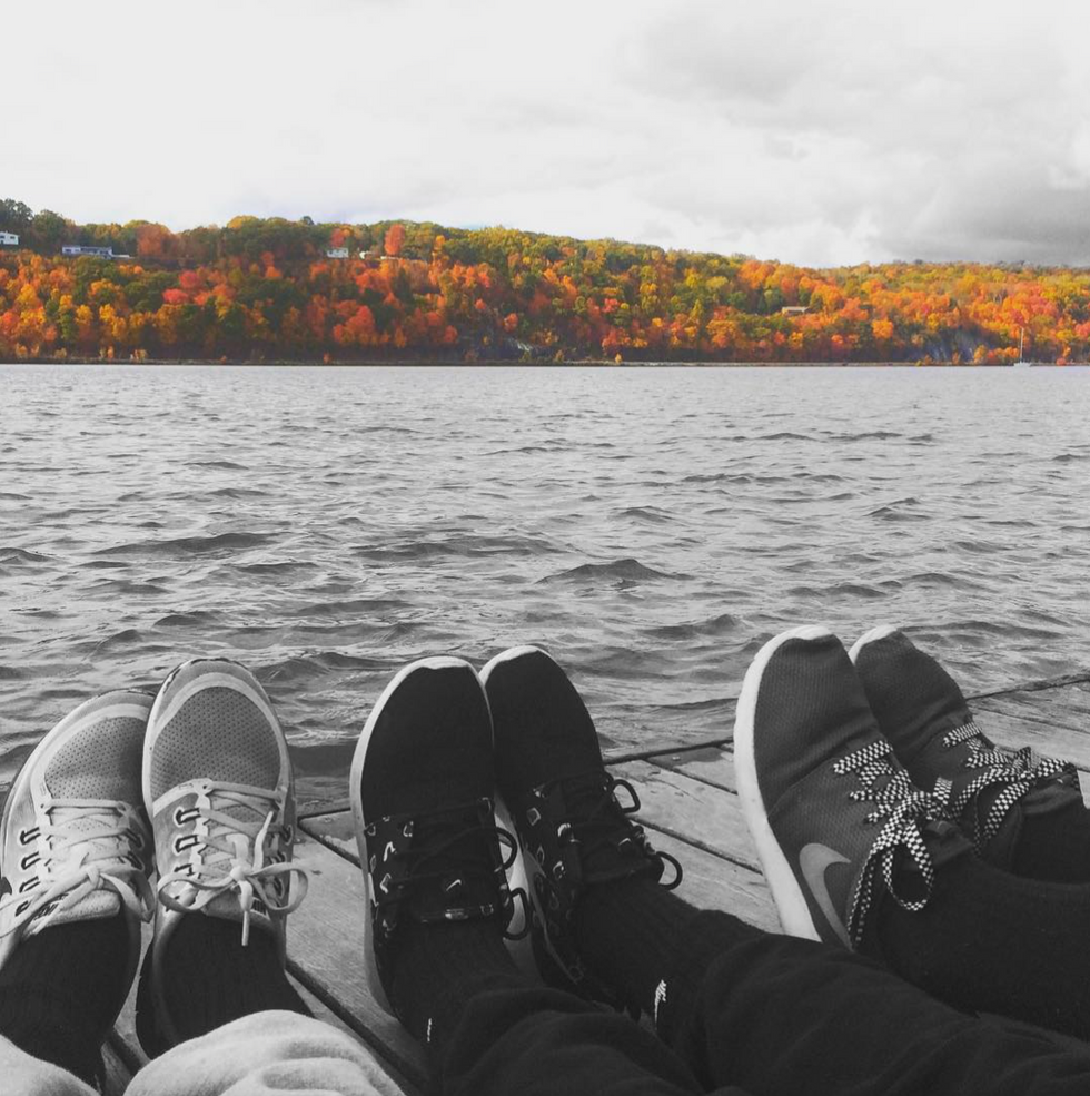 Group of friends siting on a dock enjoying the views of the autumn trees. 