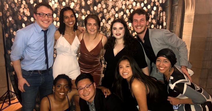 Group of nine people smiling at a party with a sparkling background.