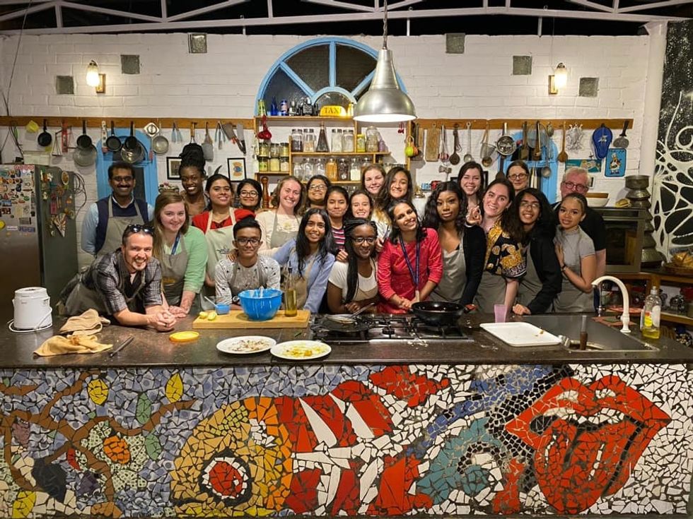 Group of students and professors from Miami University in Ohio and Christ University in India, smiling at the camera behind a food-prep table.