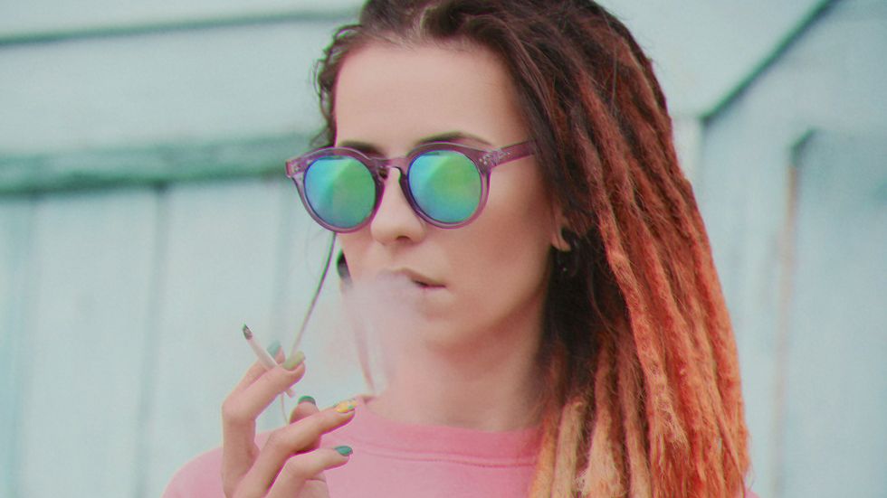 Guy smoking weed next to a window