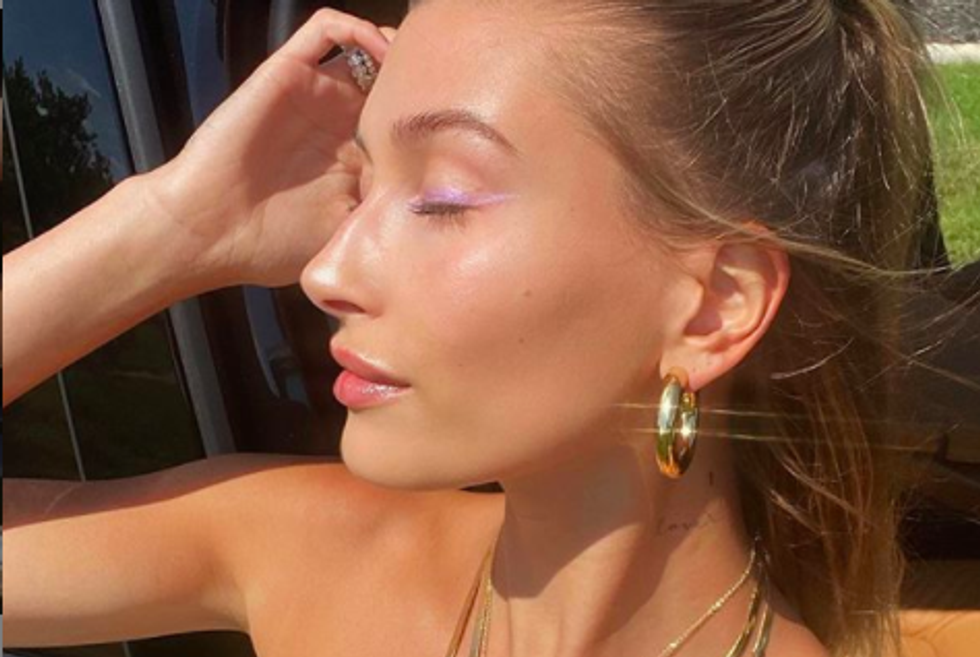 hailey bieber looking to her right with her eyes closed 