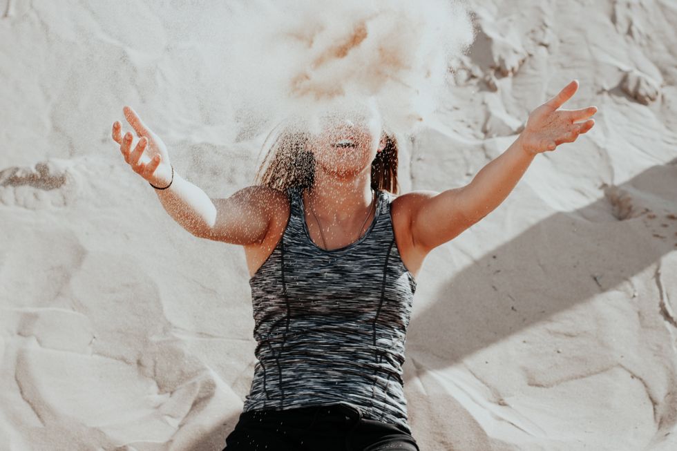happy woman throwing sand into the air