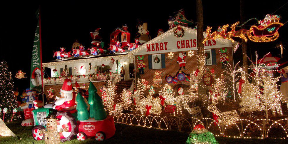 House front yard decorated with Christmas lights and inflatables.