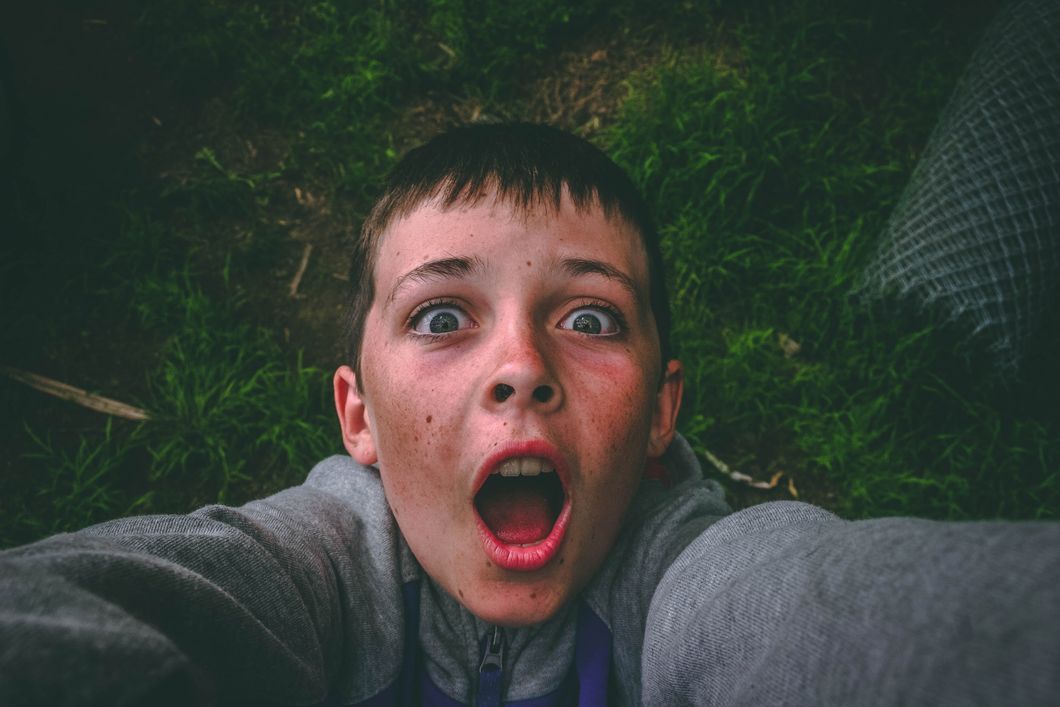 https://www.pexels.com/photo/opened-mouth-black-haired-boy-in-gray-full-zip-jacket-standing-on-grass-field-taking-selfie-848740/