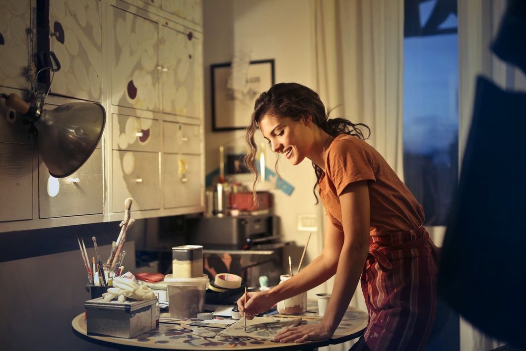 https://www.pexels.com/photo/photo-of-woman-painting-while-smiling-and-standing-by-the-table-3811830/
