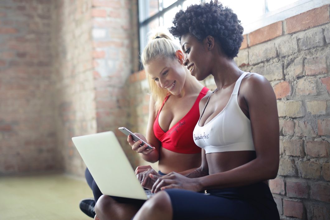 https://www.pexels.com/photo/two-women-wearing-red-and-white-sports-bras-sitting-near-brown-wall-bricks-863950/