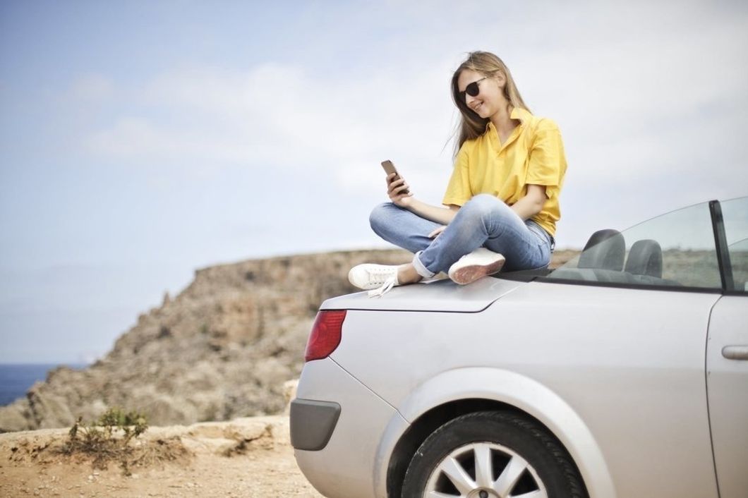 https://www.pexels.com/photo/woman-in-yellow-blouse-and-blue-jeans-taking-selfie-while-sitting-on-car-787472/