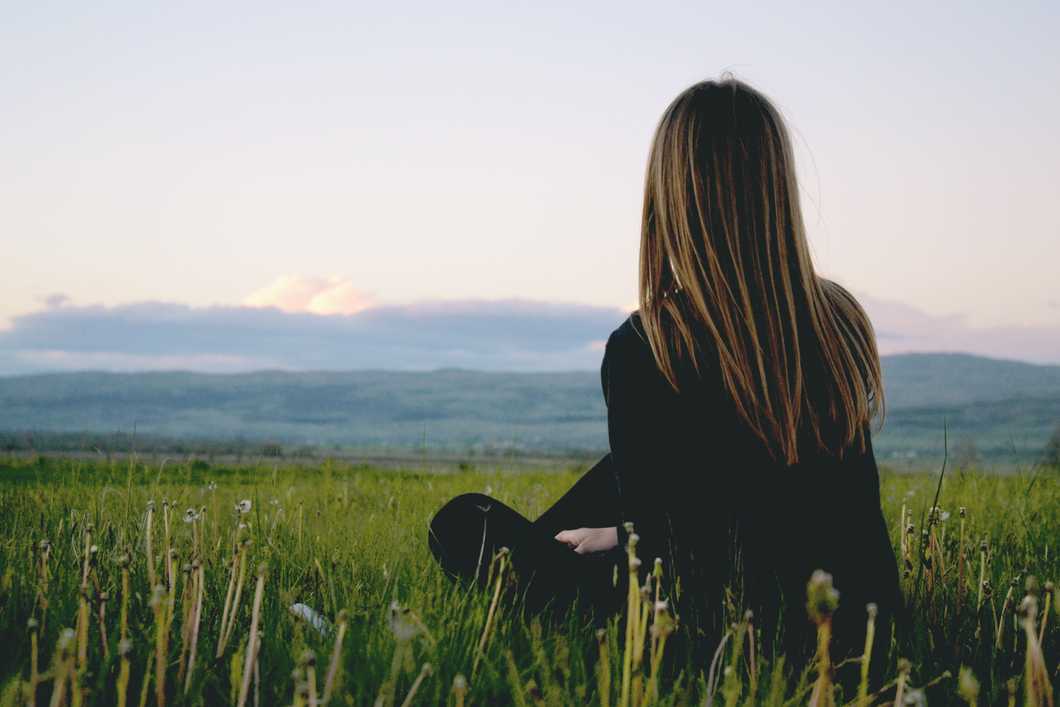 https://www.pexels.com/photo/woman-wearing-black-long-sleeved-shirt-sitting-on-green-grass-field-near-mountain-under-cloudy-sky-691919/
