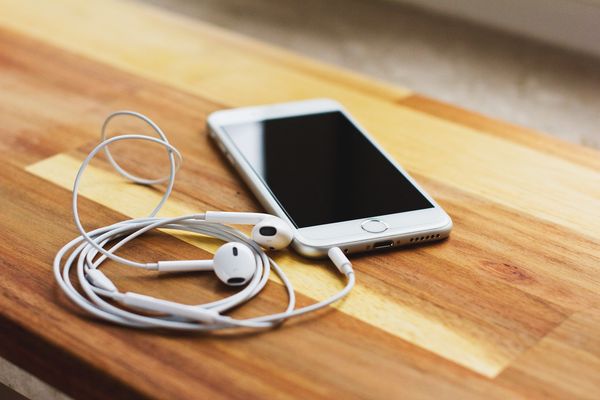 ipod with apple headphones sits on wooden table