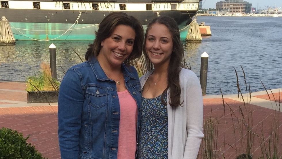 Jenna Pizzi and her mom smiling by a waterfront with a historic ship in the background.