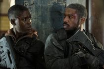 Jodie Turner-Smith (left) and Michael B. Jordan (right)  looks at each other during an intense fight scene in WITHOUT REMORSE. Both are wearing black and grey tactical gear and have minor bleeding head wounds. 