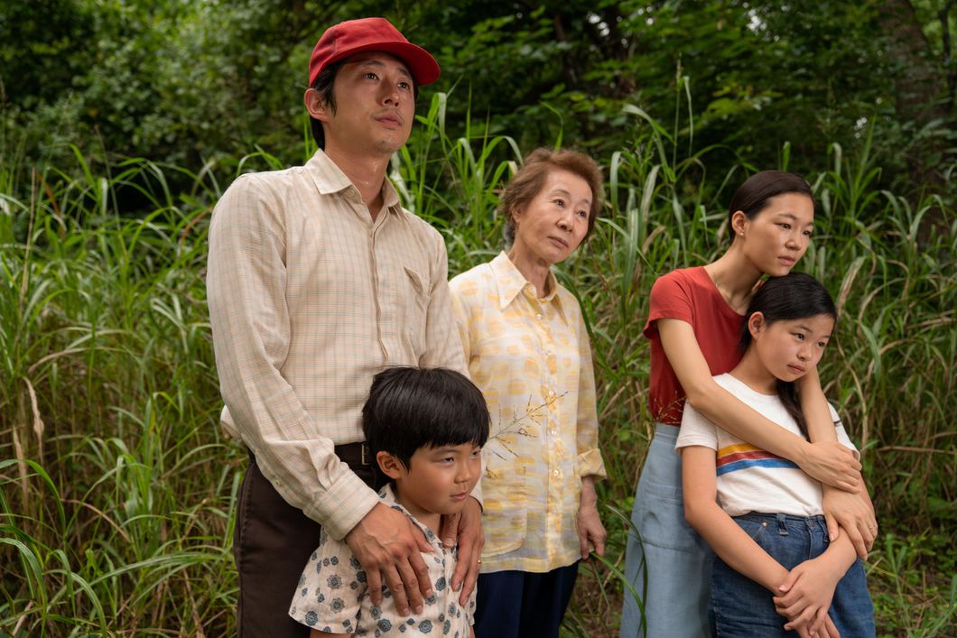(Left to right) Steven Yeun, Alan S. Kim, Yuh-Jung Youn, Yeri Han and Noel Cho in "Minari." The family stands in the foreground of some tall bright green grass.