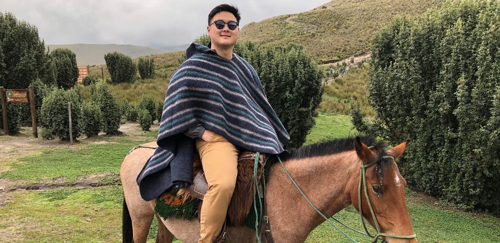Lubin in striped poncho and sunglasses riding a horse in a grassy landscape.