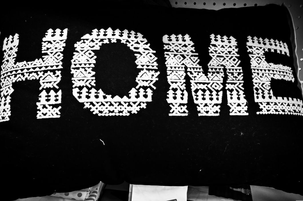 Machine embroidered white letters spelling HOME on a black pillow