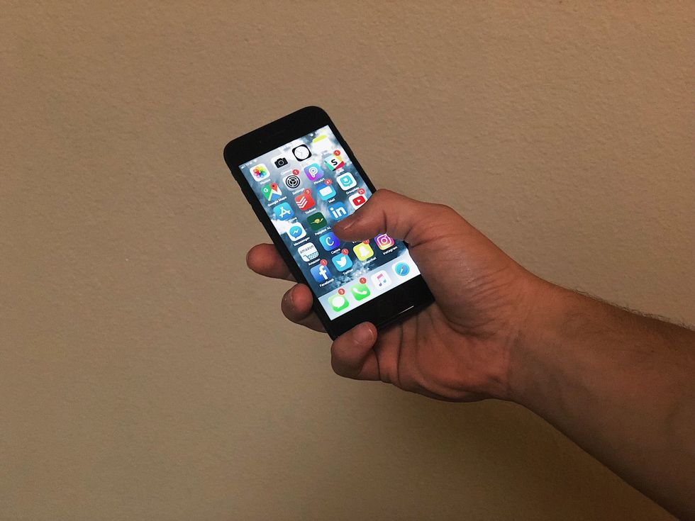 Man holding an iPhone with apps displayed on screen