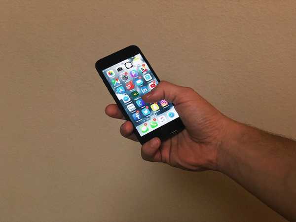 Man holding an iPhone with apps displayed on screen