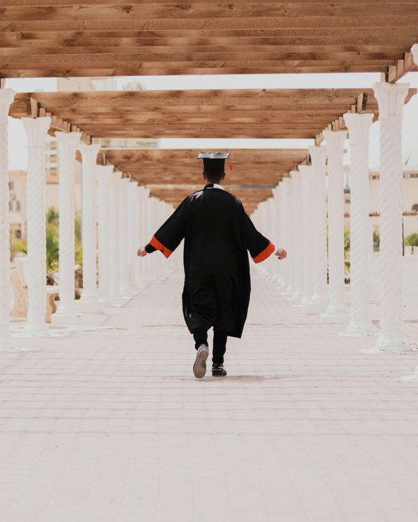 man in black long sleeve shirt and black pants walking on white concrete pathway
