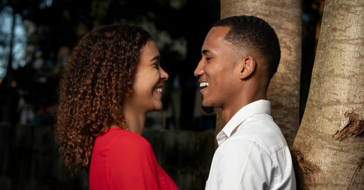 man in white dress shirt kissing woman in red dress