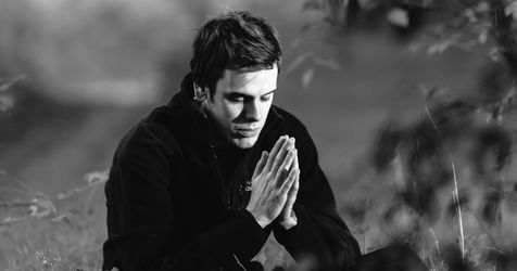 man prays in field