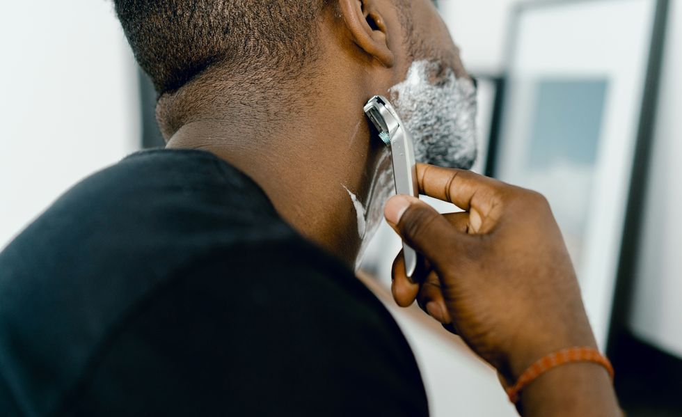 man shaving himself in front of a mirror
