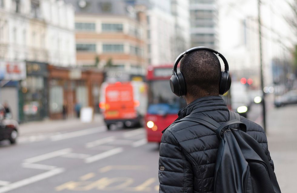 Man standing on the street waiting for the bus with headphones on