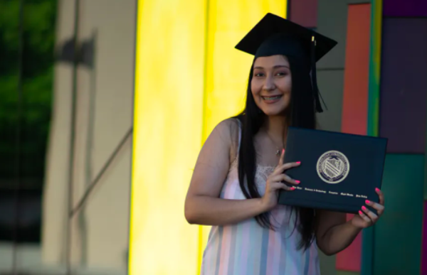 me holding a picture of my diploma with a graduation hat on