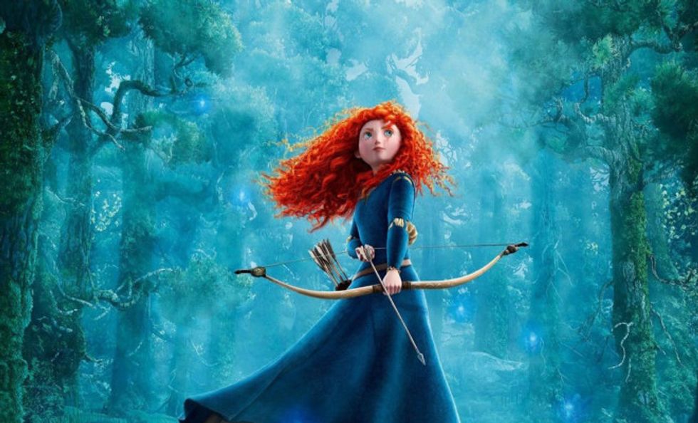 Merida from Brave holding a bow and arrow in the forest.