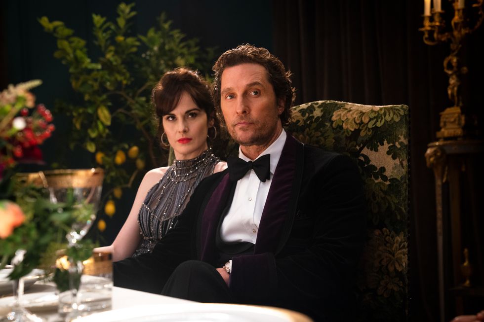 Michelle Dockery sits to Matthew McConaughey's right. They're both dressed for a fancy occasion in "The Gentlemen."
