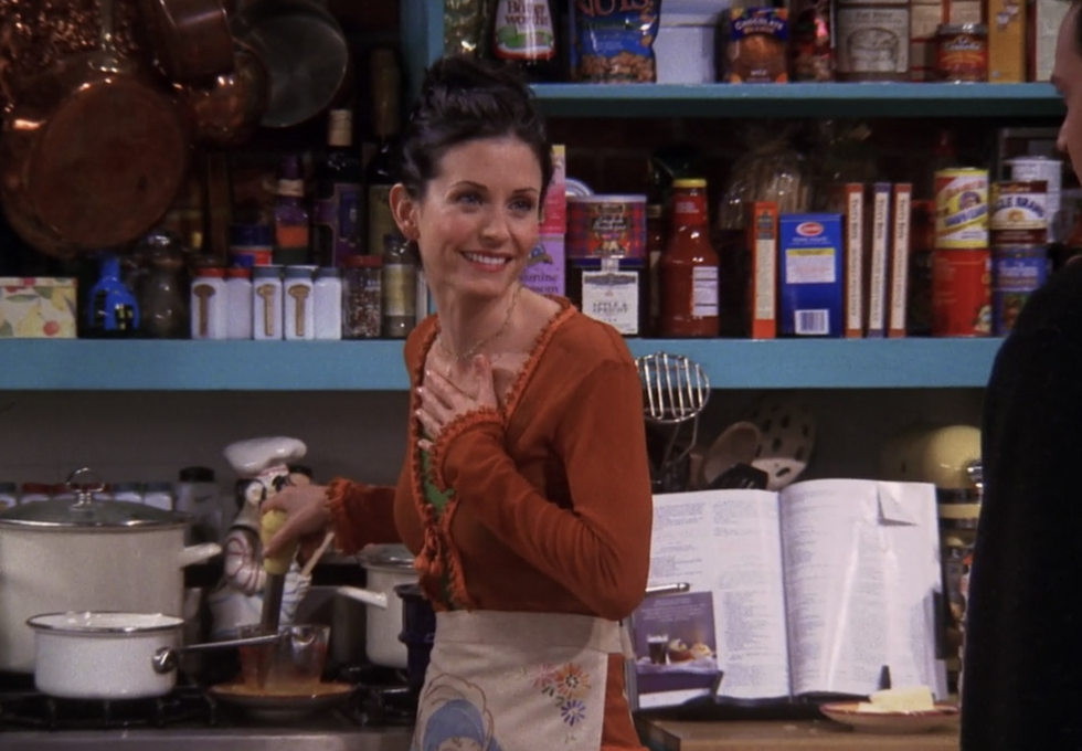 monica from friends wearing apron and smiling in kitchen