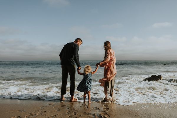 mother and father playing with child in the ocean