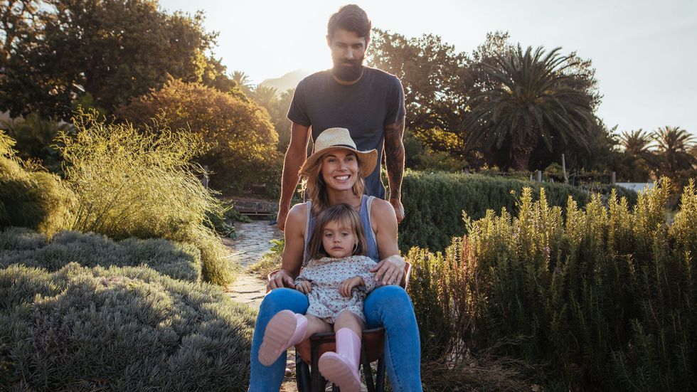 mother and father walking child in field at sunset