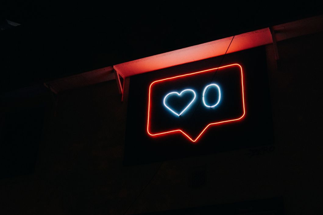 Neon sign of an Instagram like notification with a 0 next to the heart 