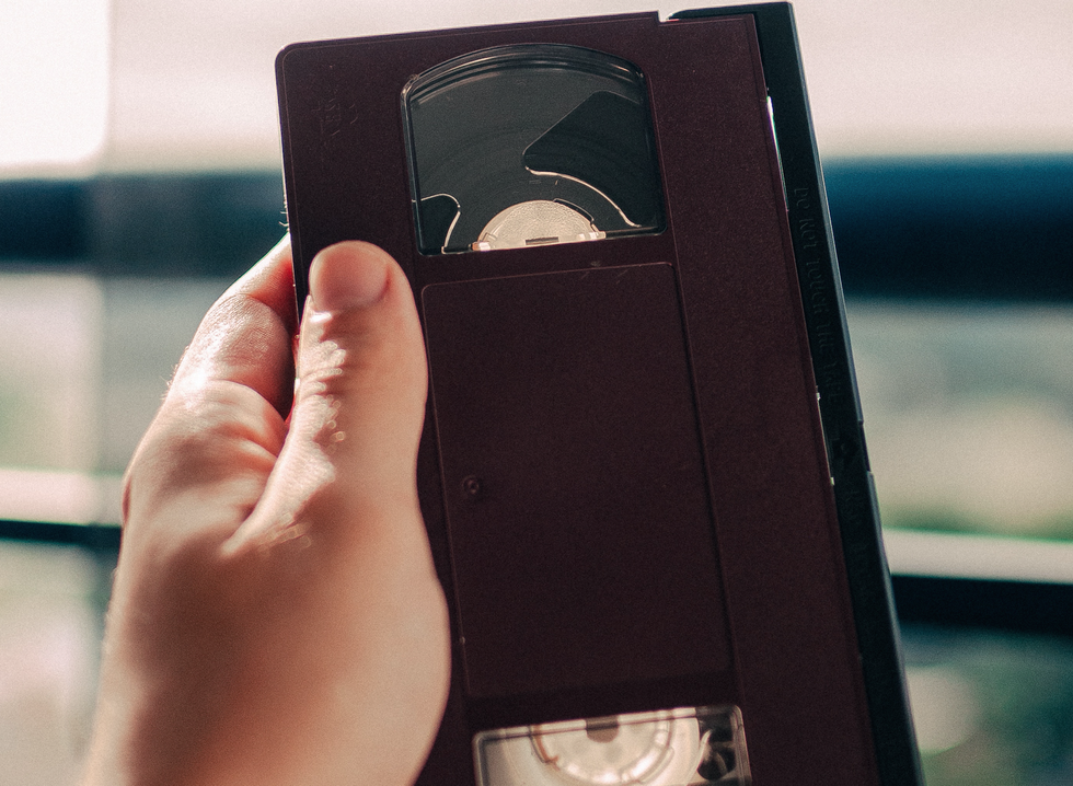 person holding black VHS tape