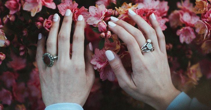person holding pink flowers in nude nail polish