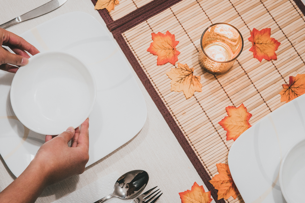 person holding round white ceramic bowl on square white ceramic plate