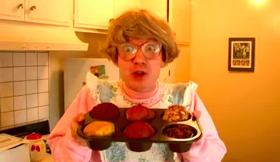 Person in kitchen holding a tray of baked muffins