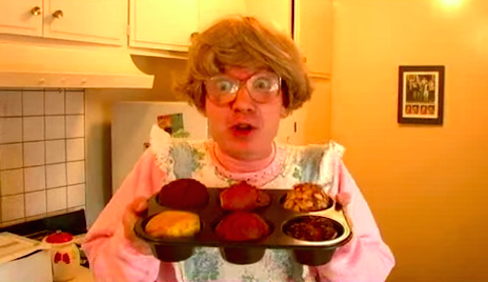 Person in kitchen holding a tray of baked muffins