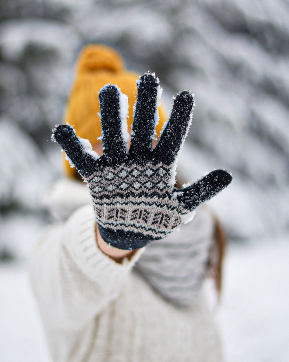 Person in white and black knit gloves.