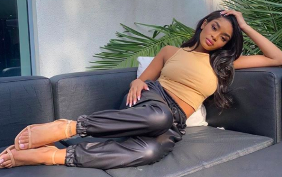 person lounging on couch wearing leather pants and nude tank