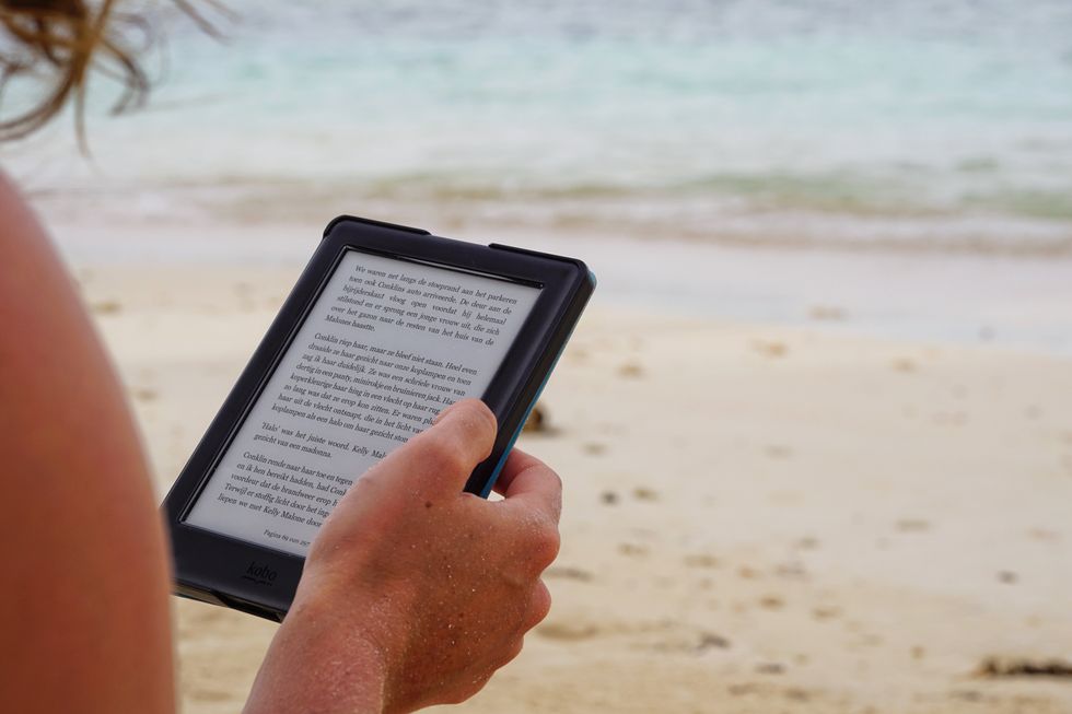 Person reading an ebook on a tablet while on the beach