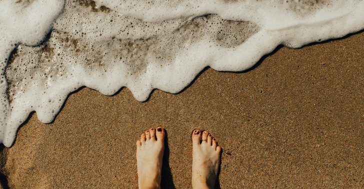person's feet on seashore