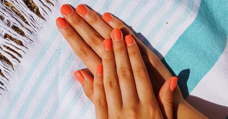 Person's orange nails putting on towel